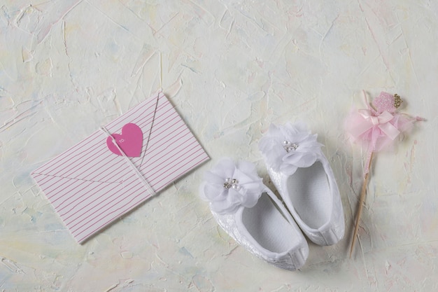 White booties made of lace for a girl and envelope with a pink heart