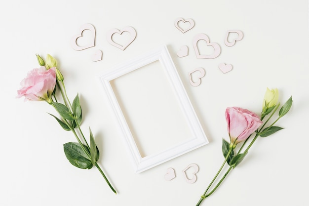 Cornice bianca con forme di cuore e fiori di eustoma su sfondo bianco