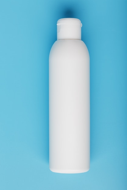 White bottle on a blue background. Free space for text.