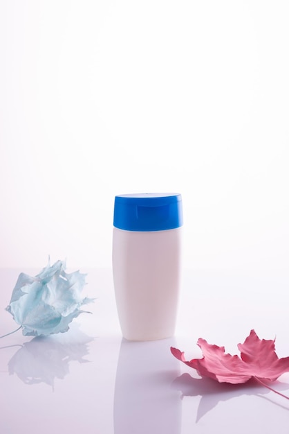 White bottle for cream with autumn leaves on white background