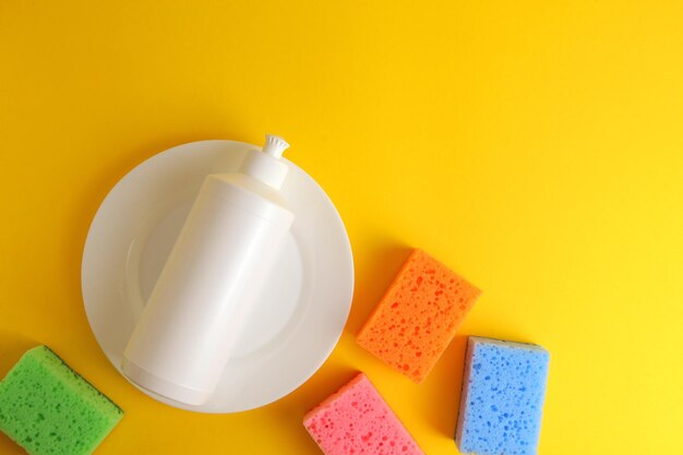 A white bottle of dish soap sits on a yellow background next to a white dish that says'clean '