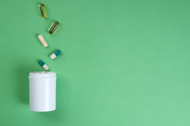 Photo a white bottle of pills is poured into a white container with the word capsules on it.