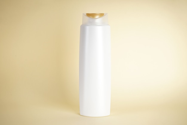 White bottle of shampoo on yellow background.