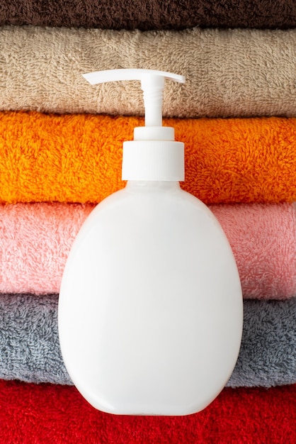 White bottle with liquid soap on top of colorful towels