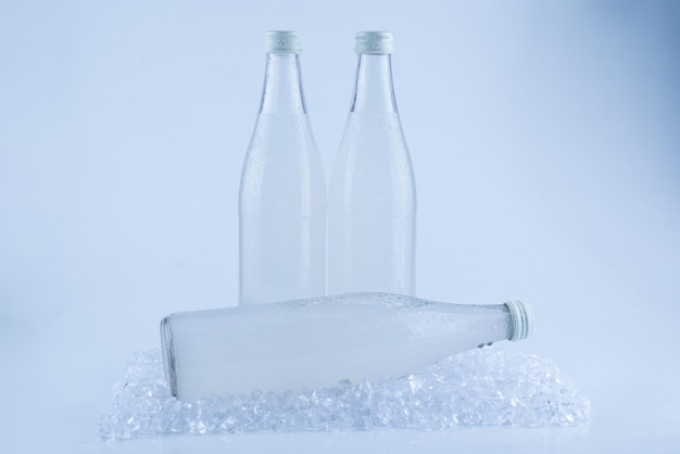 A white bottle with a soda drink on ice isolated