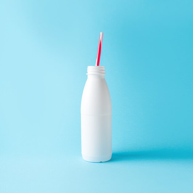 White bottle with straw on bright blue background