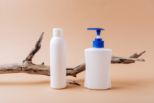 White bottles and a dry tree branch on a beige background.