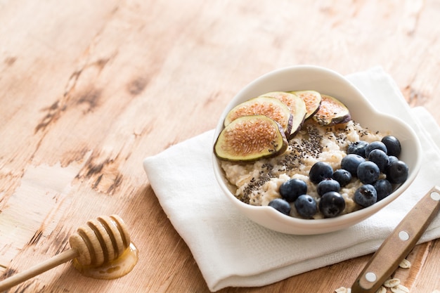 White Bowl of oats porridge with figs, blueberries and chia seeds.