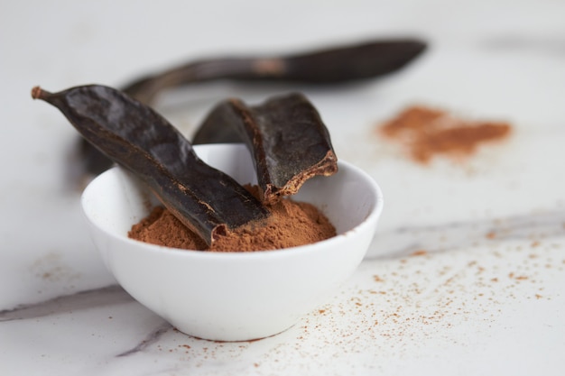 White bowl with carob powder close up