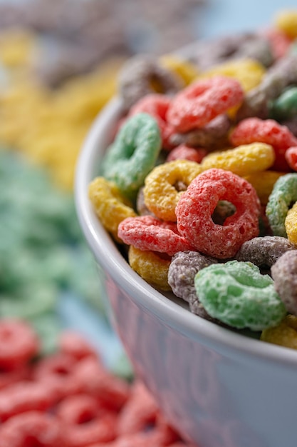 Foto ciotola bianca con cereali colorati a forma di anello e latte su uno sfondo blu