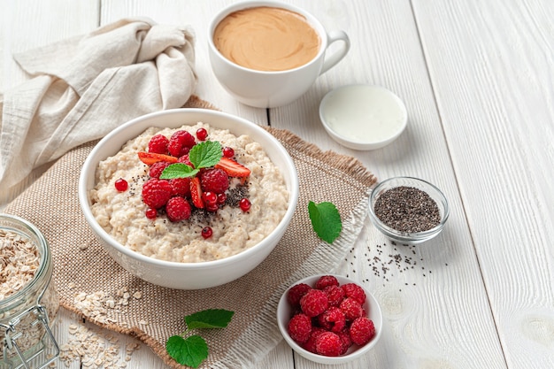 White bowl with oatmeal porridge with berries and chia seeds a
healthy breakfast