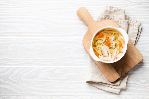 Белые чаши с теплым здоровым домашним куриным супом на обед, белый деревянный фон стола. Традиционный вкусный куриный суп полезен для здоровья и иммунной системы. Вид сверху, место для текста