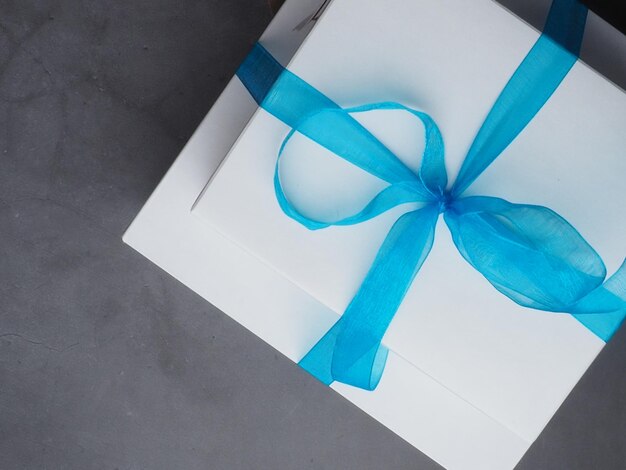 A white box with a blue ribbon tied with a bow.