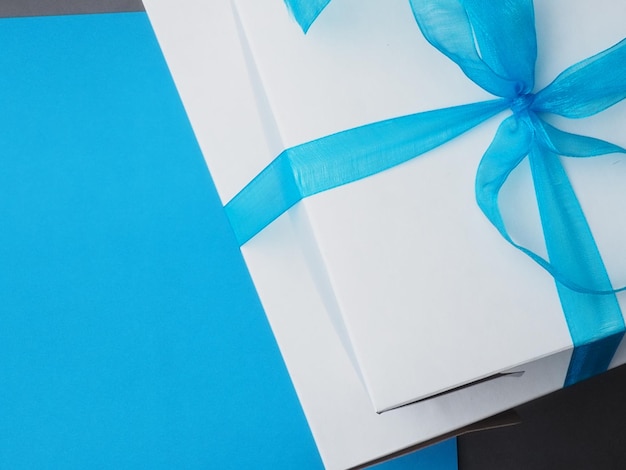 A white box with a blue ribbon tied with a bow