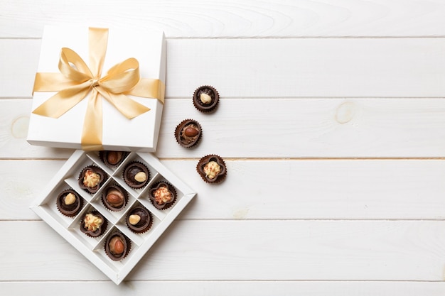 Белая коробка с шоколадными конфетами и золотой лентой, вид сверху с копией пространства