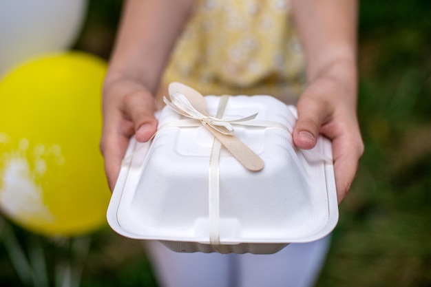 A white box with a ribbon and a wooden spoon for a bento cake in your hands