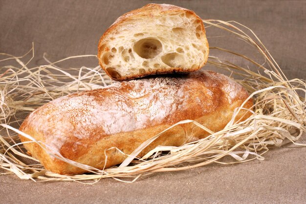 White bread lying in straw on grey linen tablecloth