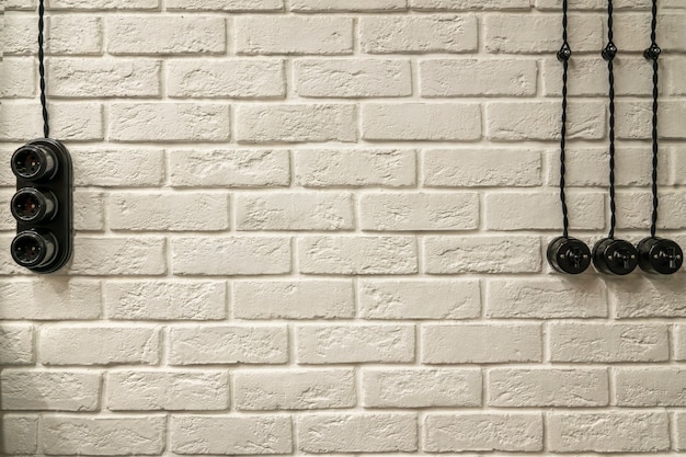 White brick textured wall, with sockets, switches and electrical wiring. loft wall