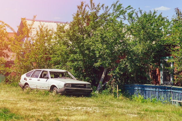 Белый разбитый автомобиль на улице в деревне