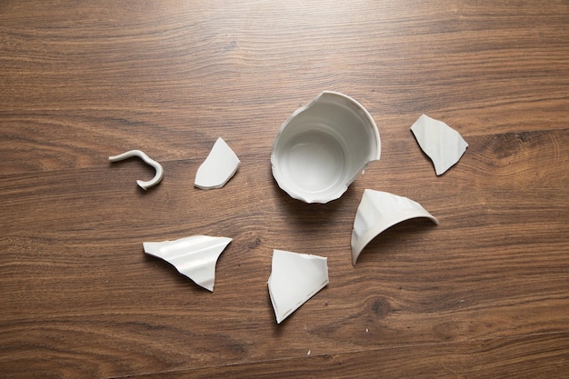 Photo white broken cup on the wooden background