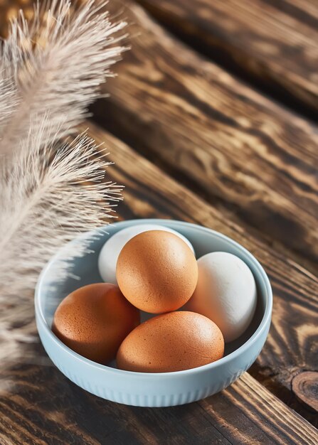 Foto uova di pasqua bianche e marroni con piume in una ciotola su un tavolo di legno scuro