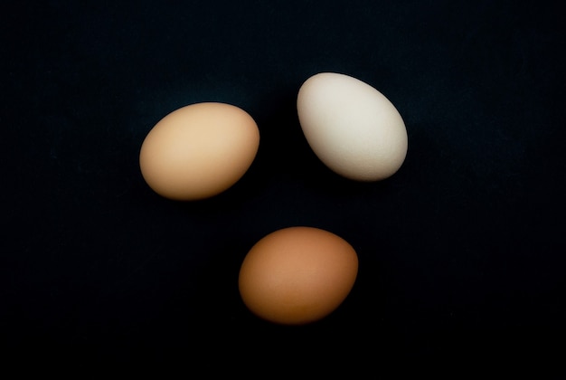 White, brown, gray chicken eggs close-up on a black background. Natural healthy nutrition all over the world.