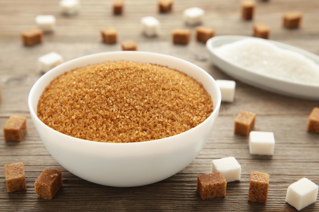 White and brown sugar in bowl on grey background Vertical photo