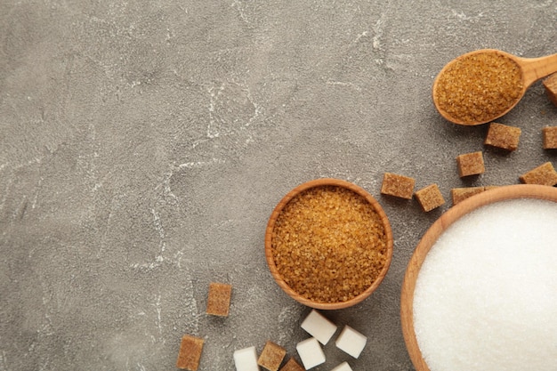 White and brown sugar in bowl on grey background