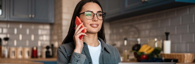 White brunette woman talking on cellphone while working with laptop