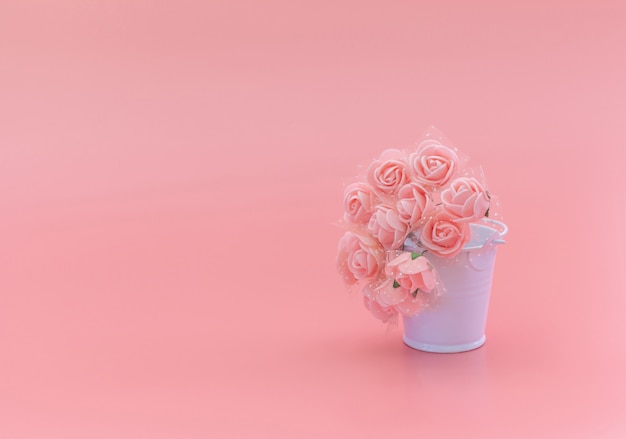 ピンクの背景、休日の概念上の花と白いバケツ