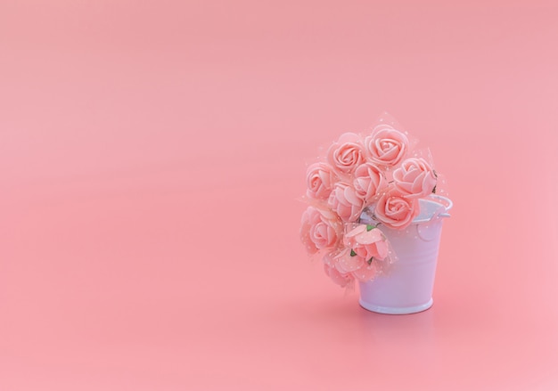 White bucket with flowers on a pink background, the concept of the holiday