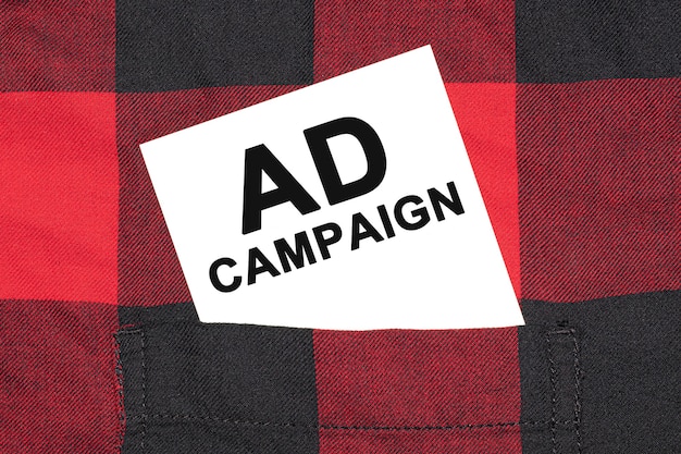 Белая визитка с текстом рекламной кампании лежит в рукаве клетчатой рубашки.