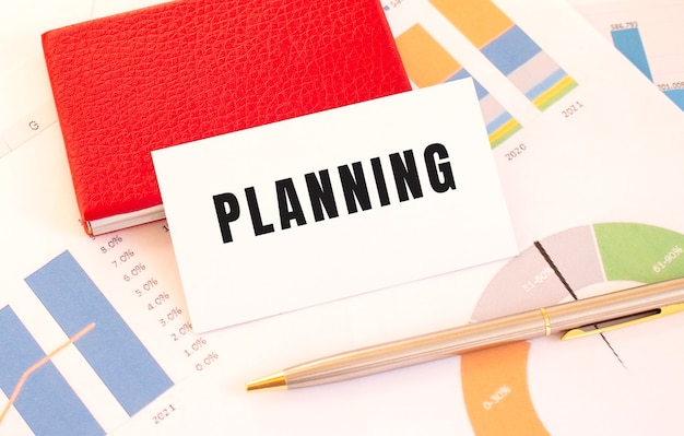 Photo white business card with text planning lies next to red business card holder.