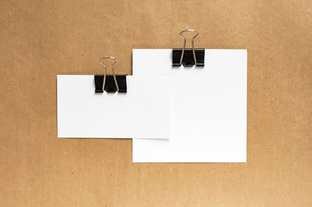 White business cards combined with a black paper clip on a kraft paper background. Top view