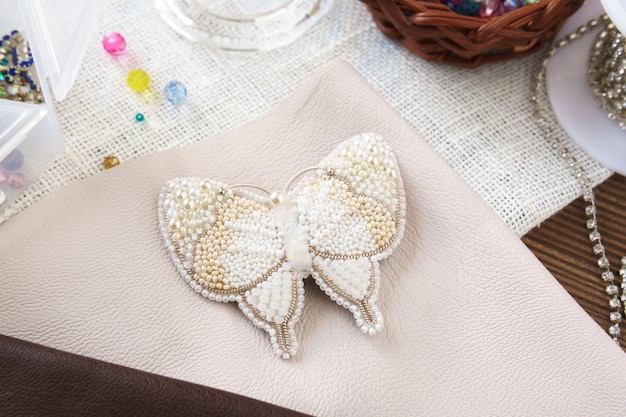 White butterfly on the table. Handmade beaded brooch on a wooden background