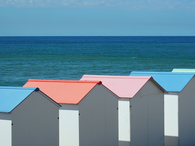 Белые кабинки для переодевания с пастельными крышами на побережье Ле-Трепор, Франция