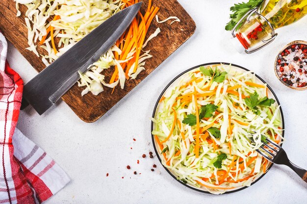 White cabbage salad coleslaw with ingredients cooking on white kitchen table background Top view copy space