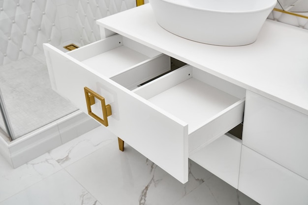 White cabinet with open drawer and vessel sink in bathroom closeup