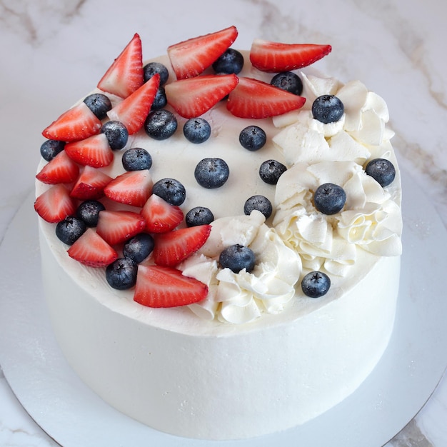 White cake decorated with raw strawberries and blueberries sweet dessert