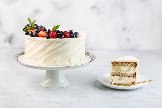 Torta bianca con una corona di frutti di bosco su fondo bianco