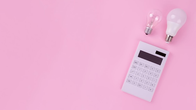 White calculator and incandescent lamp or LED bulb on pink background the payment of electricity