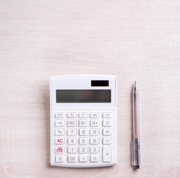 White calculator and pen on bright wooden table analytics and statistics of financial profit investment risk concept copy space top view flat lay