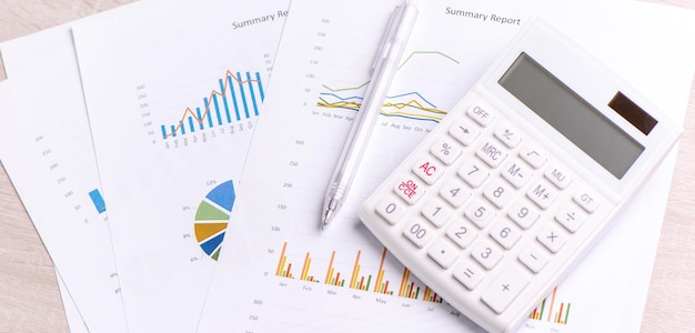 White calculator and report with chart and graph concept of annual financial profit overview banking and investment close up copy space macro