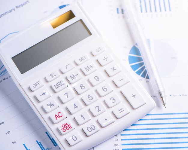 White calculator and report with chart and graph concept of annual financial profit overview banking and investment copy space macro close up