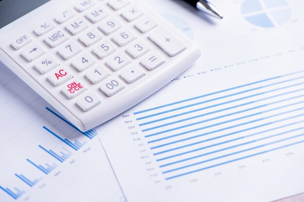 Белый калькулятор и отчет с диаграммой и графиком, концепция годового обзора финансовой прибыли, банковское дело и инвестиции