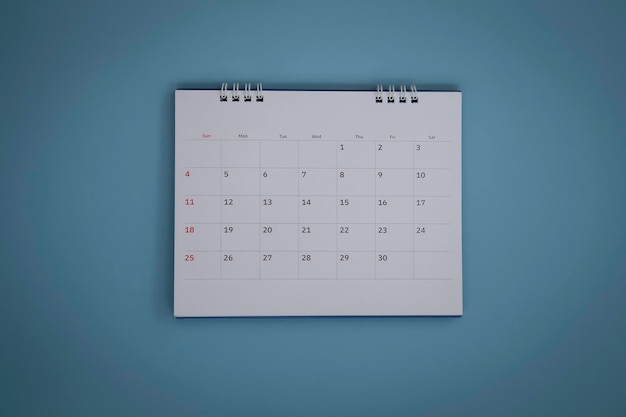 White calendar laying on blue background planning concept