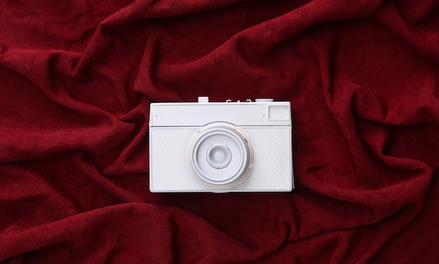 White camera on red silk background Minimalism