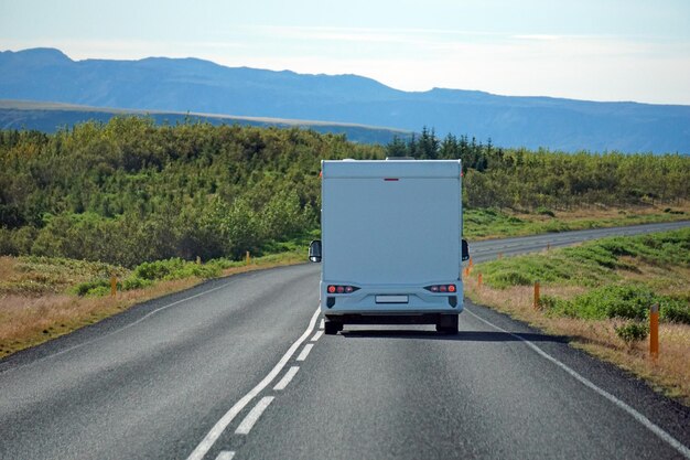 White camper driving on a road back view