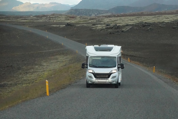 White camper driving on a road front view