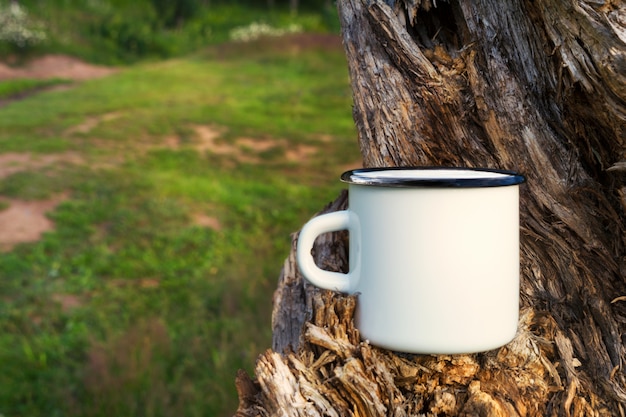 White campfire enamel mug mockup with tree stump